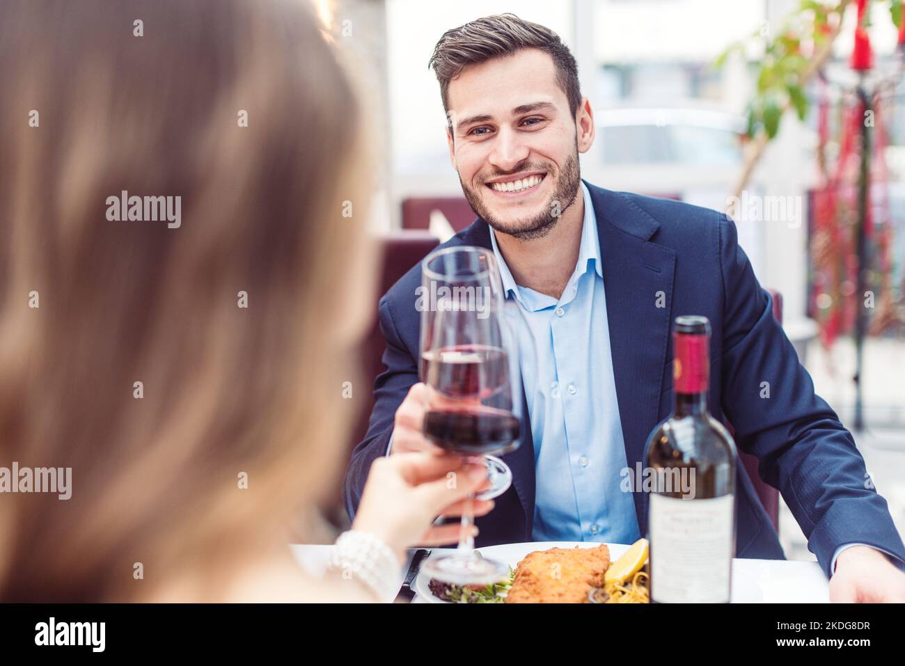 Uomo e donna che gustano un bicchiere di vino rosso con il loro pasto Foto Stock