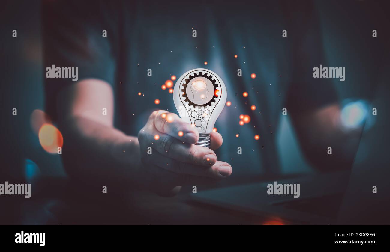 Mano dell'uomo che usa il computer e la lampadina di tenuta con un'icona dell'ingranaggio in esso, l'idea di ​​inspiration dalla tecnologia in linea. Concetto di idea di innovazione. Foto Stock
