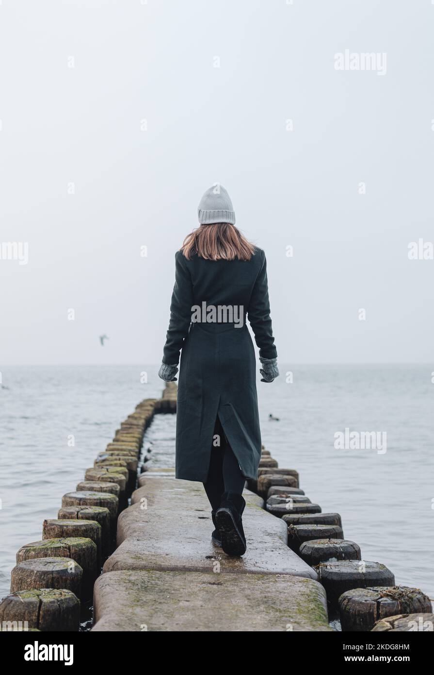 Donna su Groynes nel Mar Baltico durante l'inverno Foto Stock