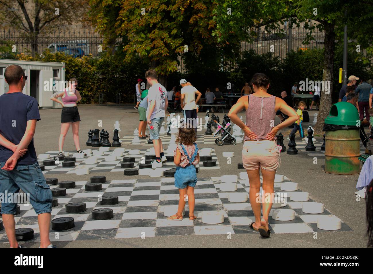 Giovane ragazza che impara a giocare a dama con i suoi genitori Foto Stock