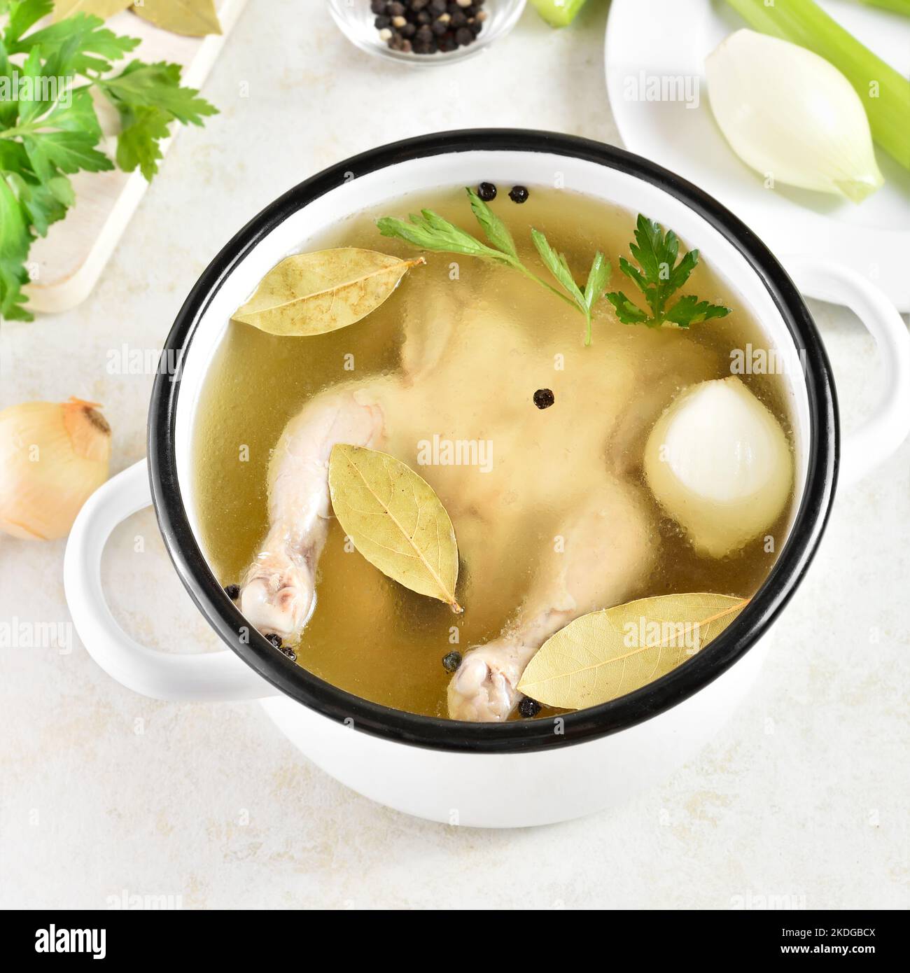 Vista ravvicinata del brodo di pollo con verdure e spezie su uno sfondo di pietra chiaro. Piatto di dieta sana per cena. Foto Stock