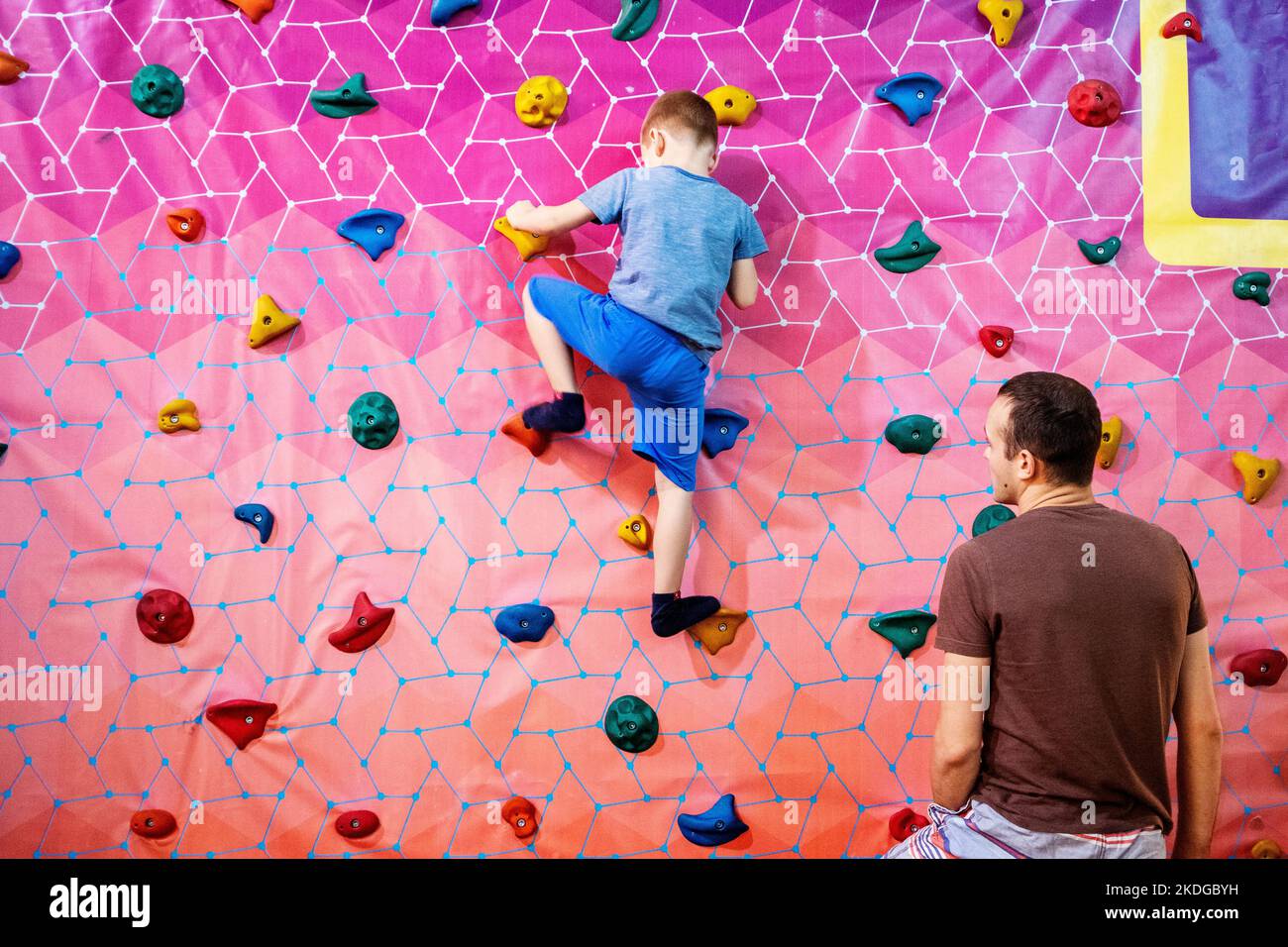 papà e figlio salgono la parete della parete di arrampicata Foto Stock