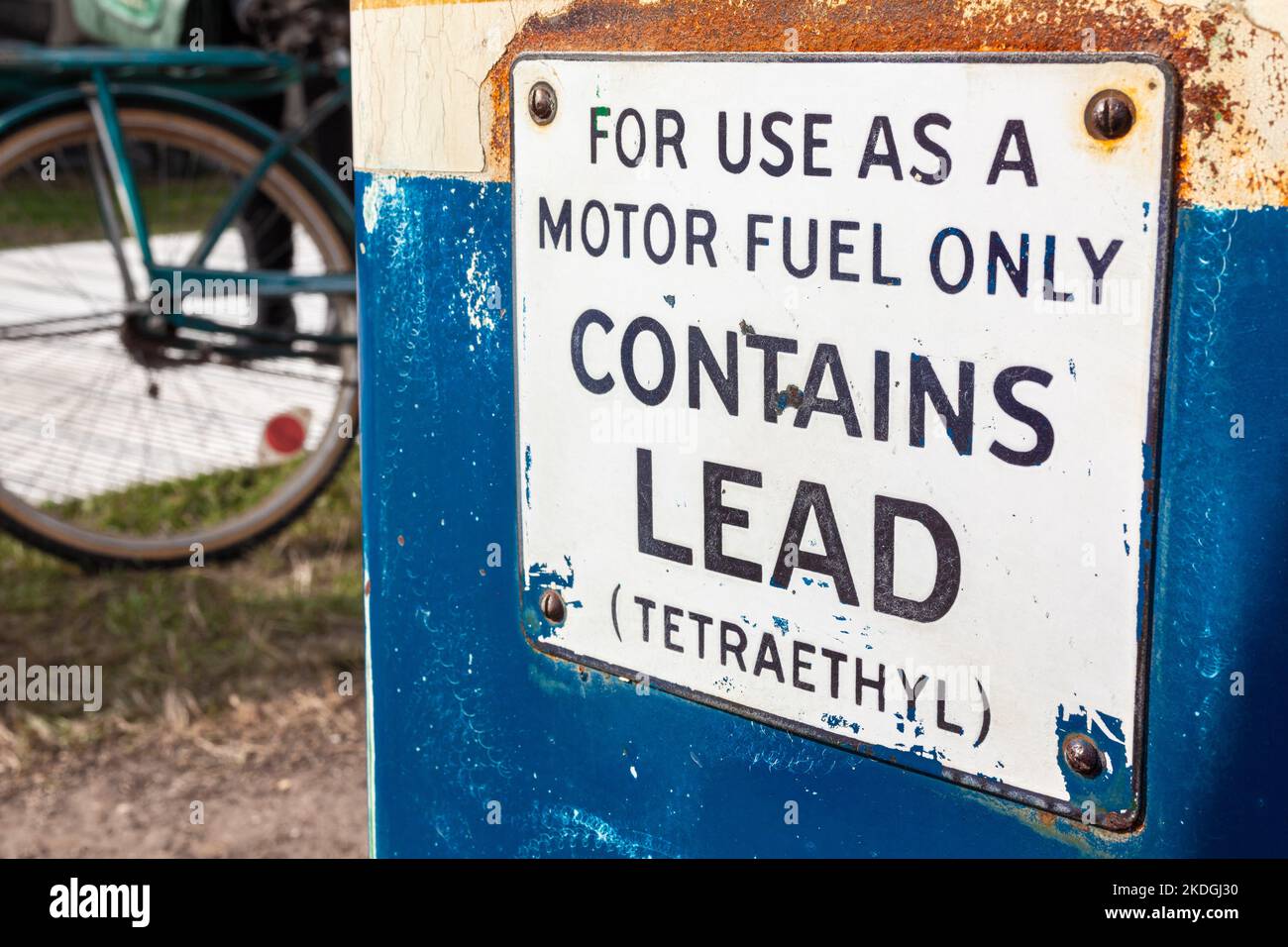Pompa benzina, benzina o benzina vecchio stile con segnale di avvertimento di piombo e Tetraetil e una bicicletta sullo sfondo Foto Stock