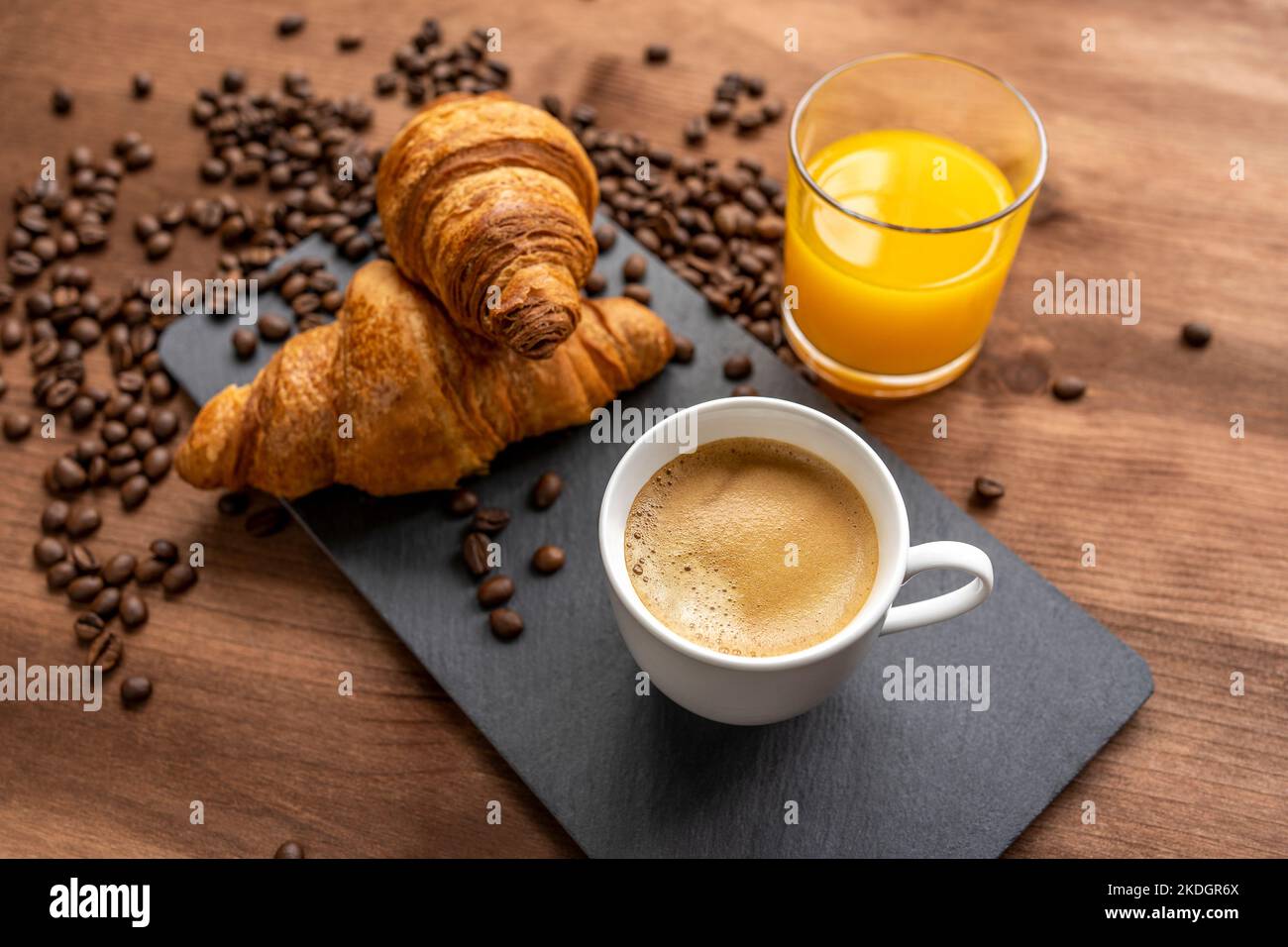 caffè caldo e due croissant e succo d'arancia su un tavolo di legno, approccio selettivo. Foto Stock