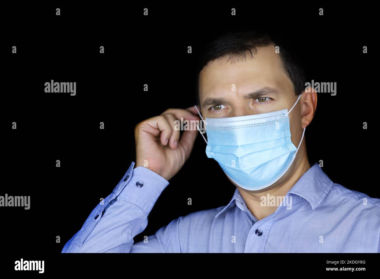 Ritratto di uomo bianco in maschera protettiva su sfondo nero. Sicurezza durante la pandemia di coronavirus Foto Stock