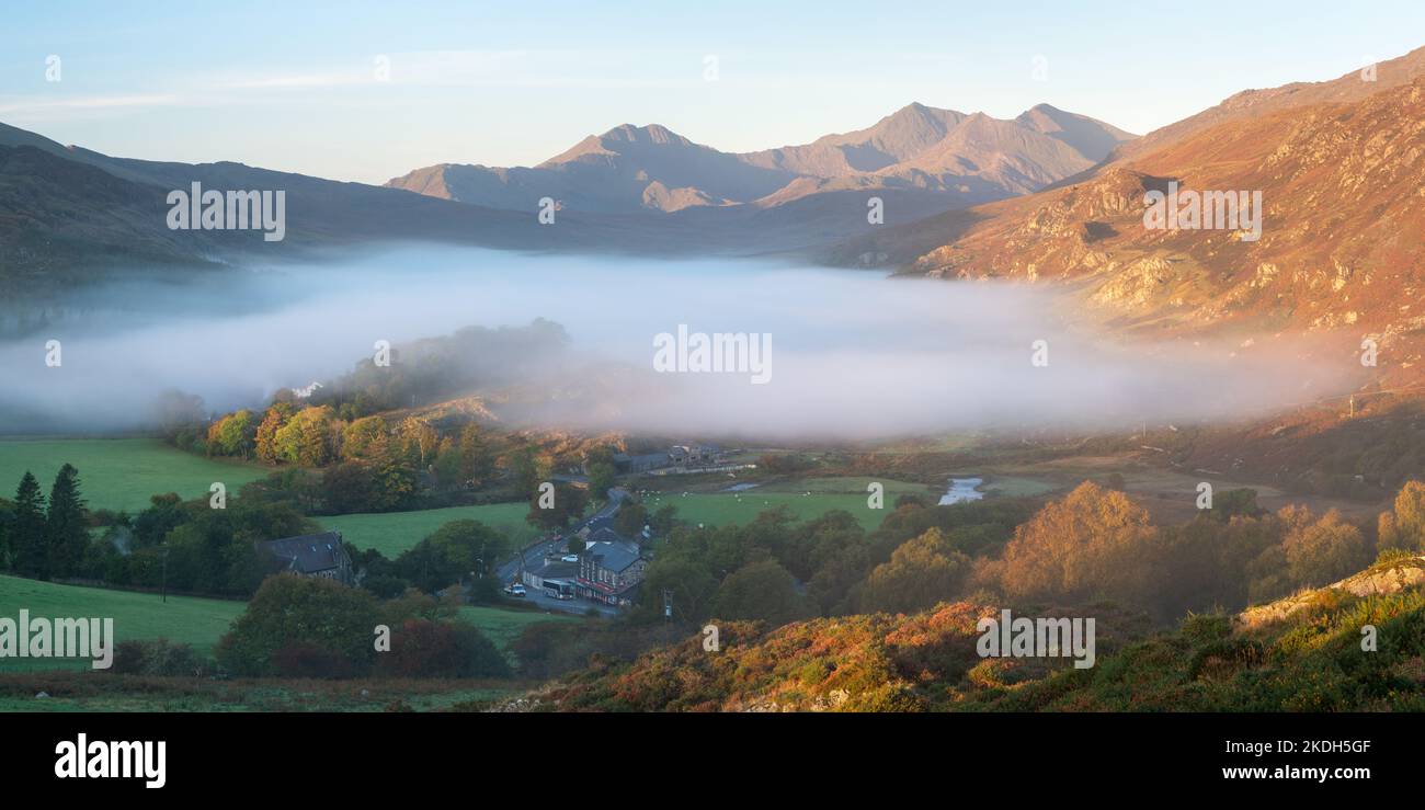 La nebbia che pende su Llynnau Mymbyr si sposta e si espande verso la prima luce diretta del mattino, con il Sowdon Horseshoe che domina la valle sottostante. Foto Stock