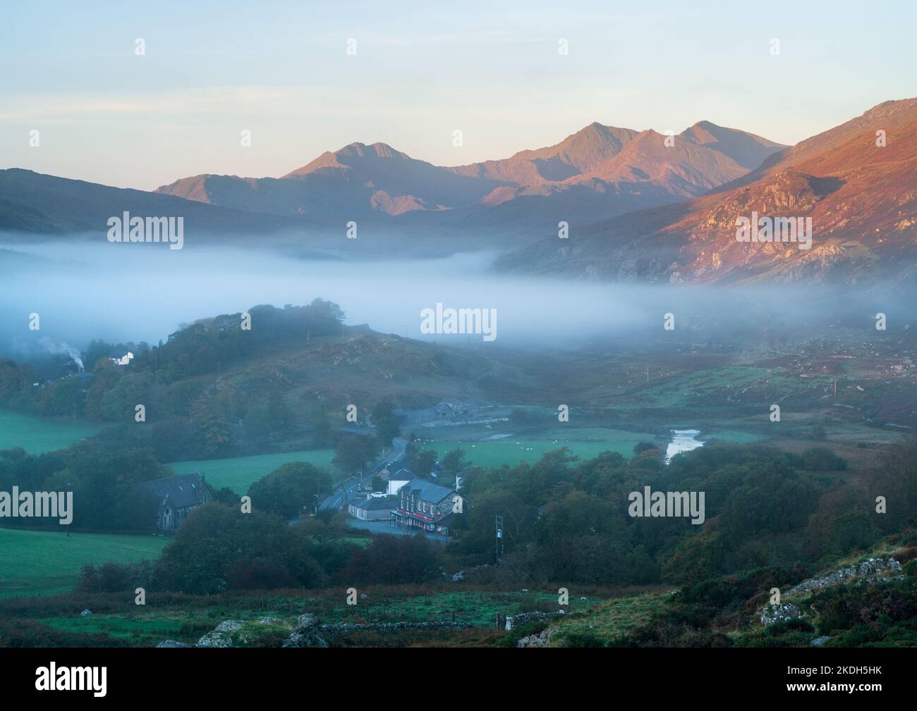 Il sole che sorge fa risplendere lo Snowdon Horseshoe, mentre la valle sotto la montagna conserva le sue fresche sfumature mentre attende la luce diretta. Foto Stock
