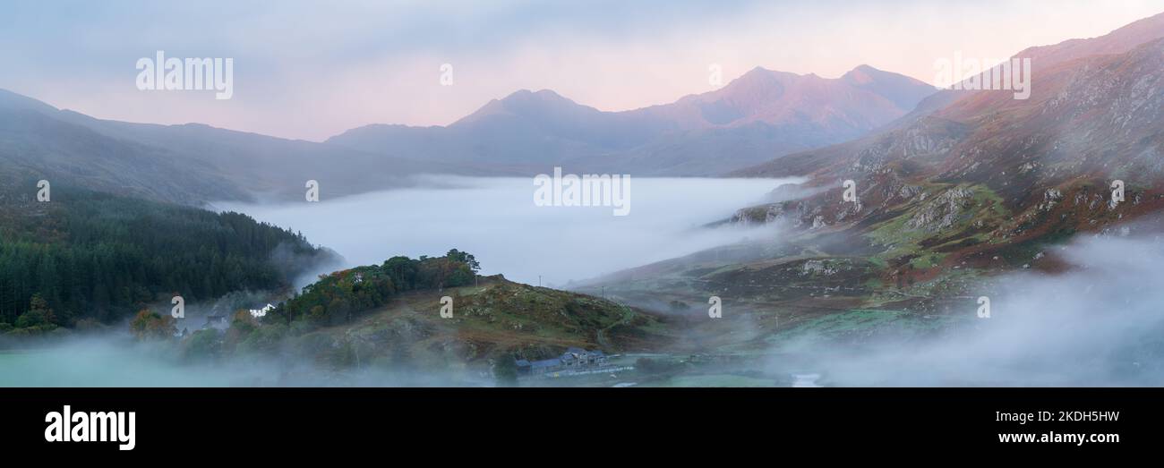 Il ferro di cavallo di Snowdon si illumina di rosso mentre il sole che sorge mette in risalto la vetta più alta di Snowdonia sopra Dyffryn Mymbyr e il paesaggio misterico vicino a Capel Curig. Foto Stock
