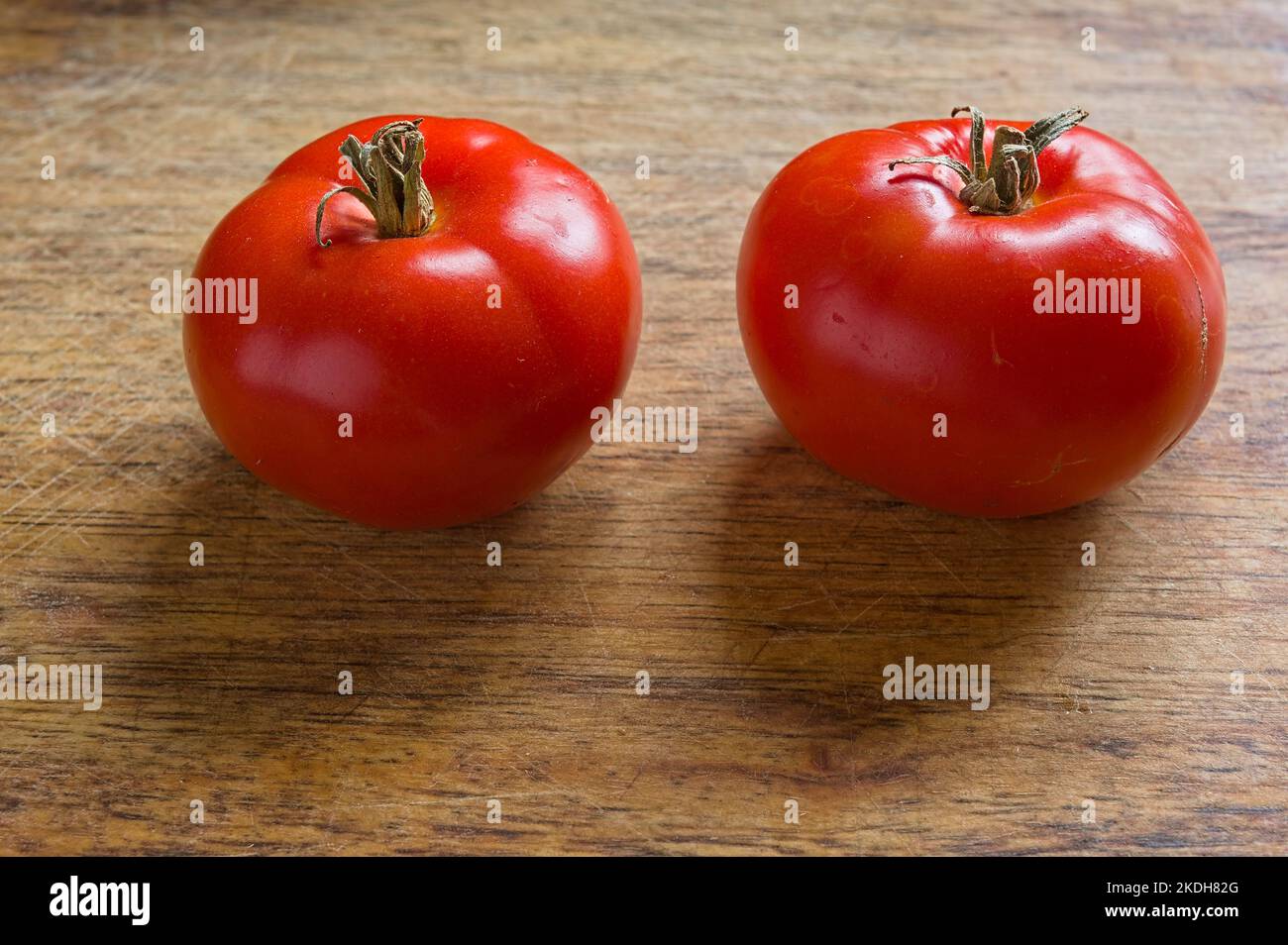 Due pomodori di vite molto maturi con fondo in legno Foto Stock