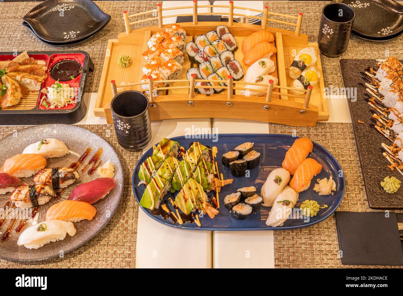 Set di piatti di pesce, sushi di tutti i tipi, gyozas giapponesi, riso e nori alghe, salmone norvegese e tonno almadraba e bicchieri con sake Foto Stock