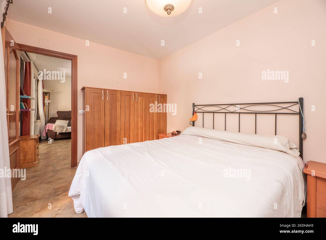 Camera con letto matrimoniale, testata in metallo nero e pavimento in marmo Foto Stock