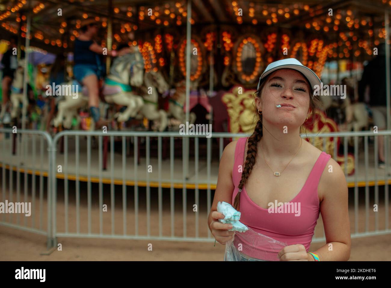 L'adolescente sorride mentre mangia la caramella di cotone davanti al carnevale Foto Stock