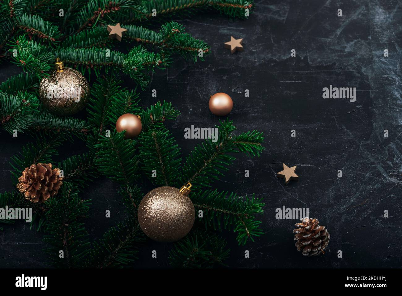 Rami d'albero di Natale, baubles dorati e coni di pino su sfondo nero. Concetto di Capodanno. Vista dall'alto, spazio di copia. Foto Stock