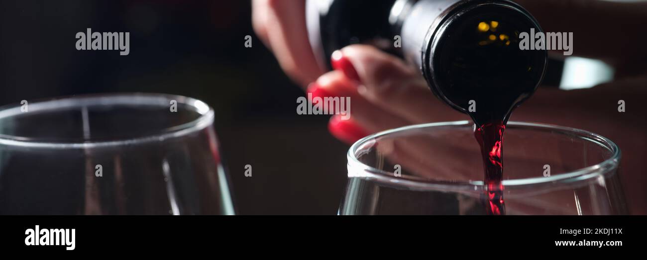 La donna versa il vino rosso in due bicchieri da primo piano Foto Stock