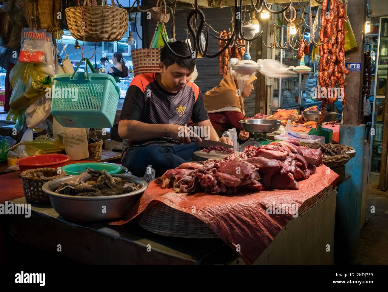 Un uomo affetta carne di manzo alla sua stalla macellaio all'interno del mercato centrale a Siem Reap, Cambogia. Foto Stock