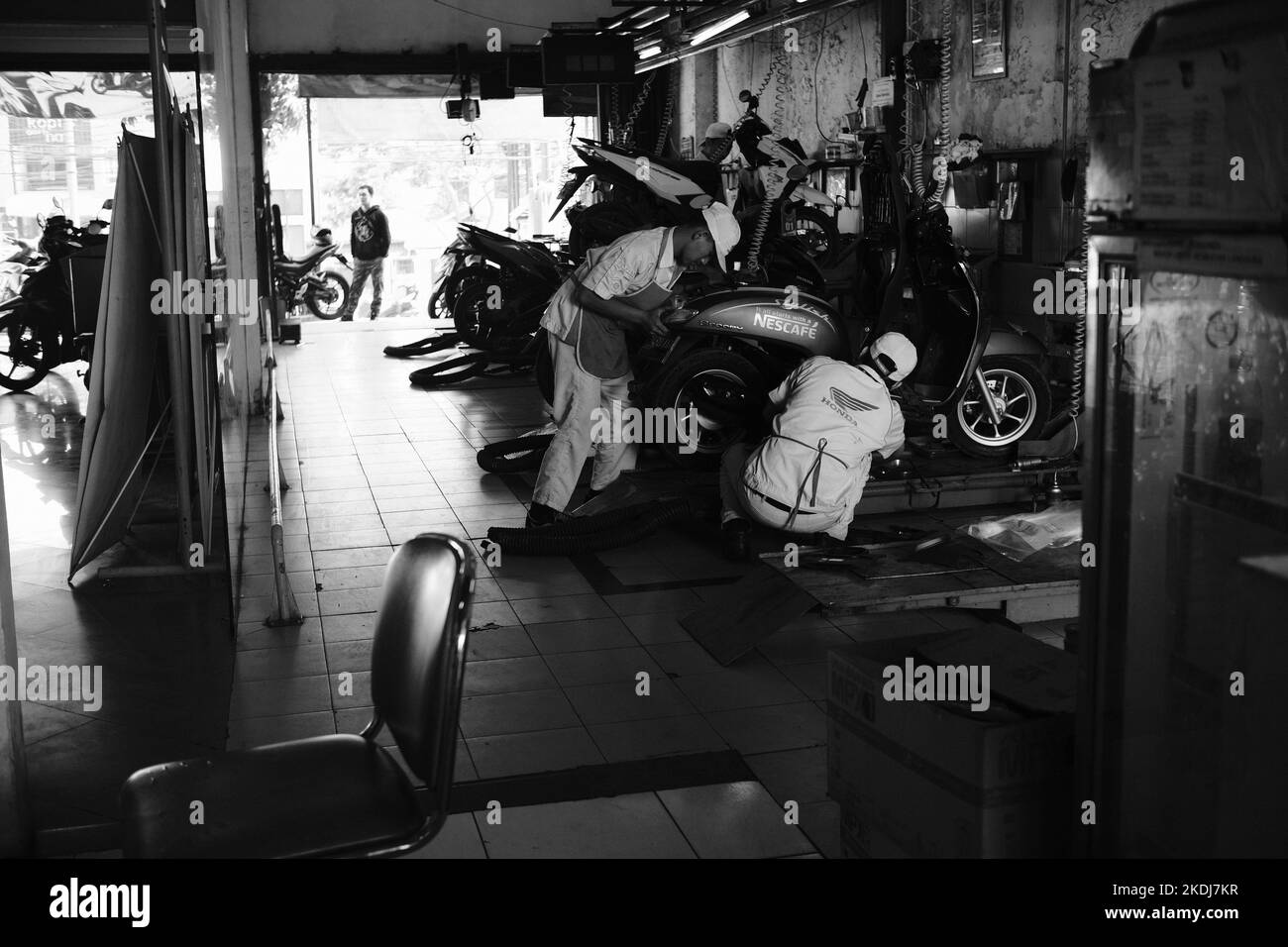 Cikancung, West Java, Indonesia - 24 Ottobre, 2022 : Foto in bianco e nero, Foto monocromatica di un meccanico che ripara una moto Foto Stock