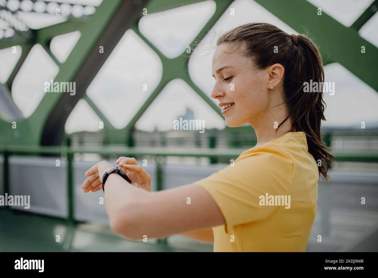 Giovane donna che controlla smartwatch in città, preparandosi per la corsa, stile di vita sano e concetto di sport. Foto Stock