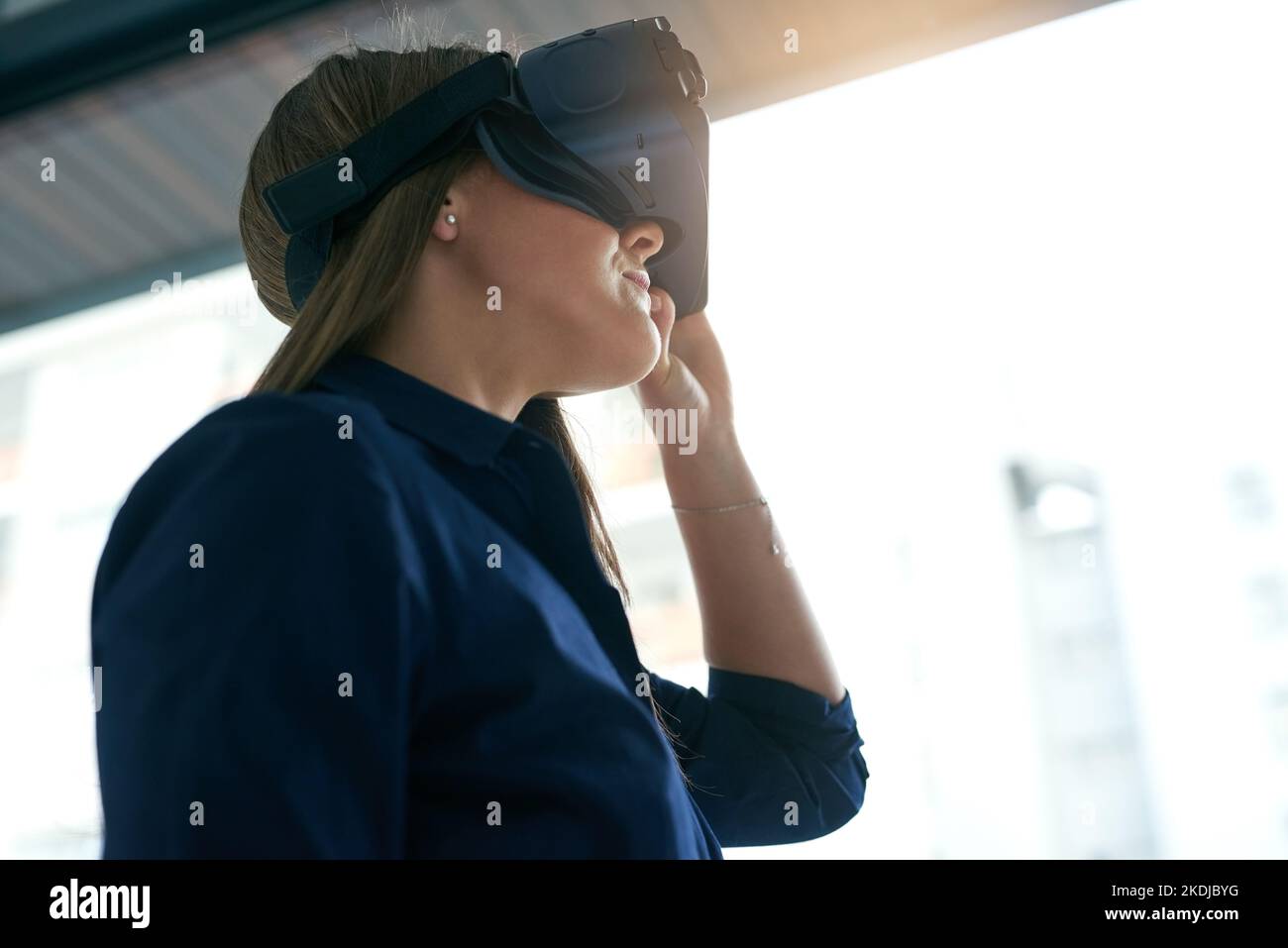 La realtà virtuale non è più solo un sogno: Una giovane donna d'affari che indossa un visore VR in ufficio. Foto Stock