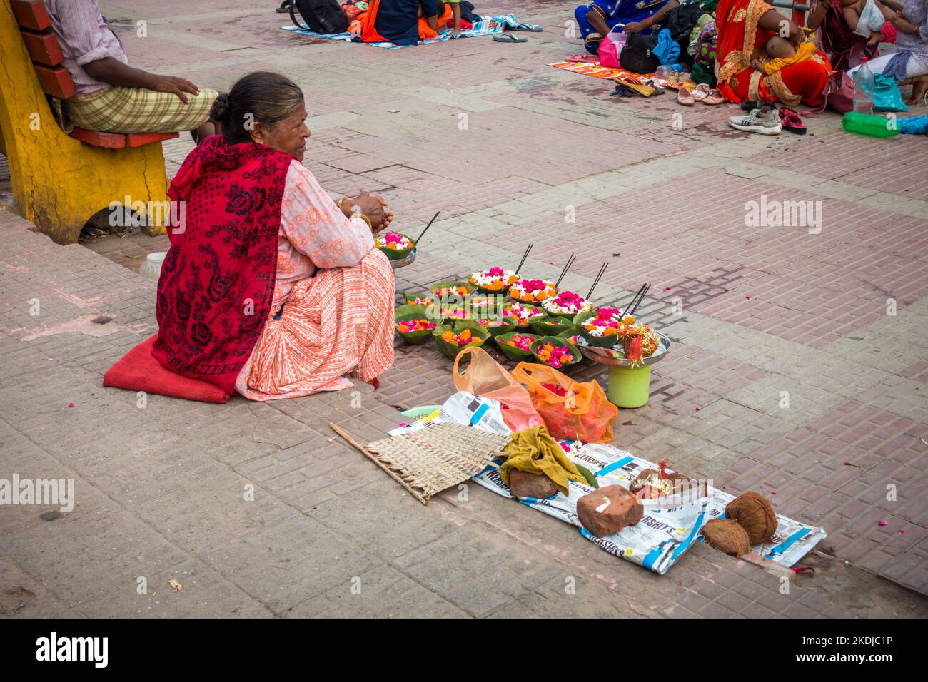 Luglio 8th 2022 Haridwar India. Una vecchia signora che vende colorato cesto di fiori sulle rive o ghat del fiume Gange per i rituali indù. Foto Stock