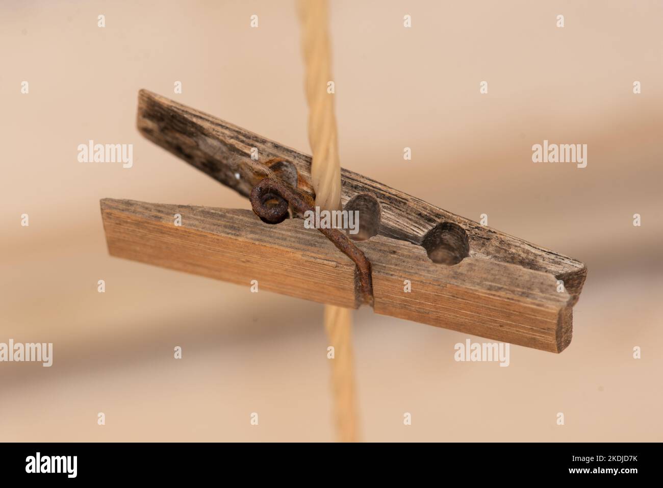 Una linea di vecchi pioli di legno su una linea di lavaggio di nylon con molle di metallo arrugginite rendono una disposizione attraente contro uno sfondo scuro e cremoso Foto Stock