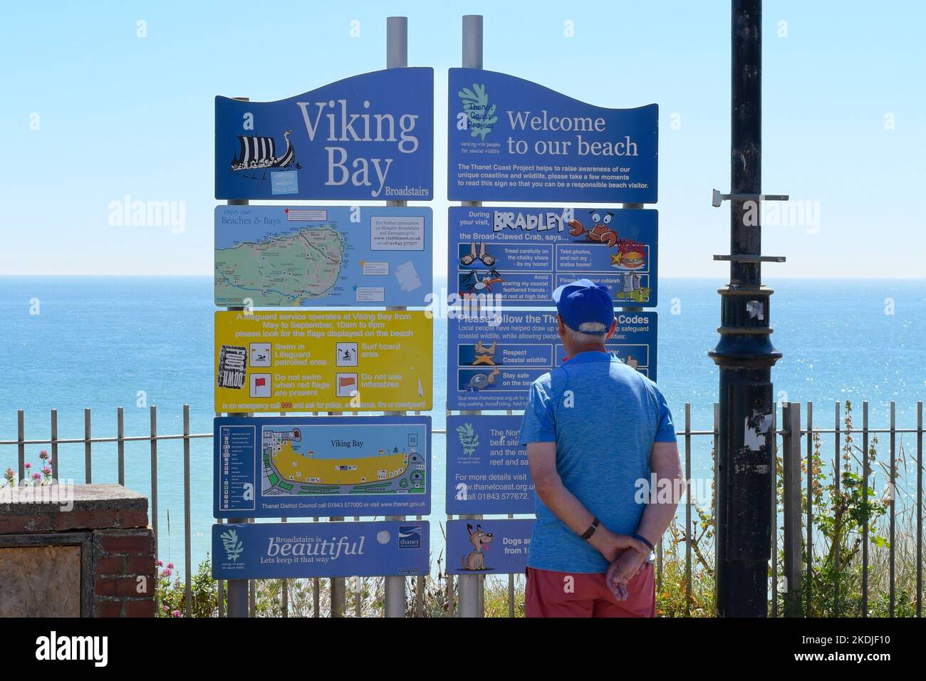Man Reading Information Board a Viking Bay Beach, Broadstairs, Kent, Inghilterra, Regno Unito Foto Stock