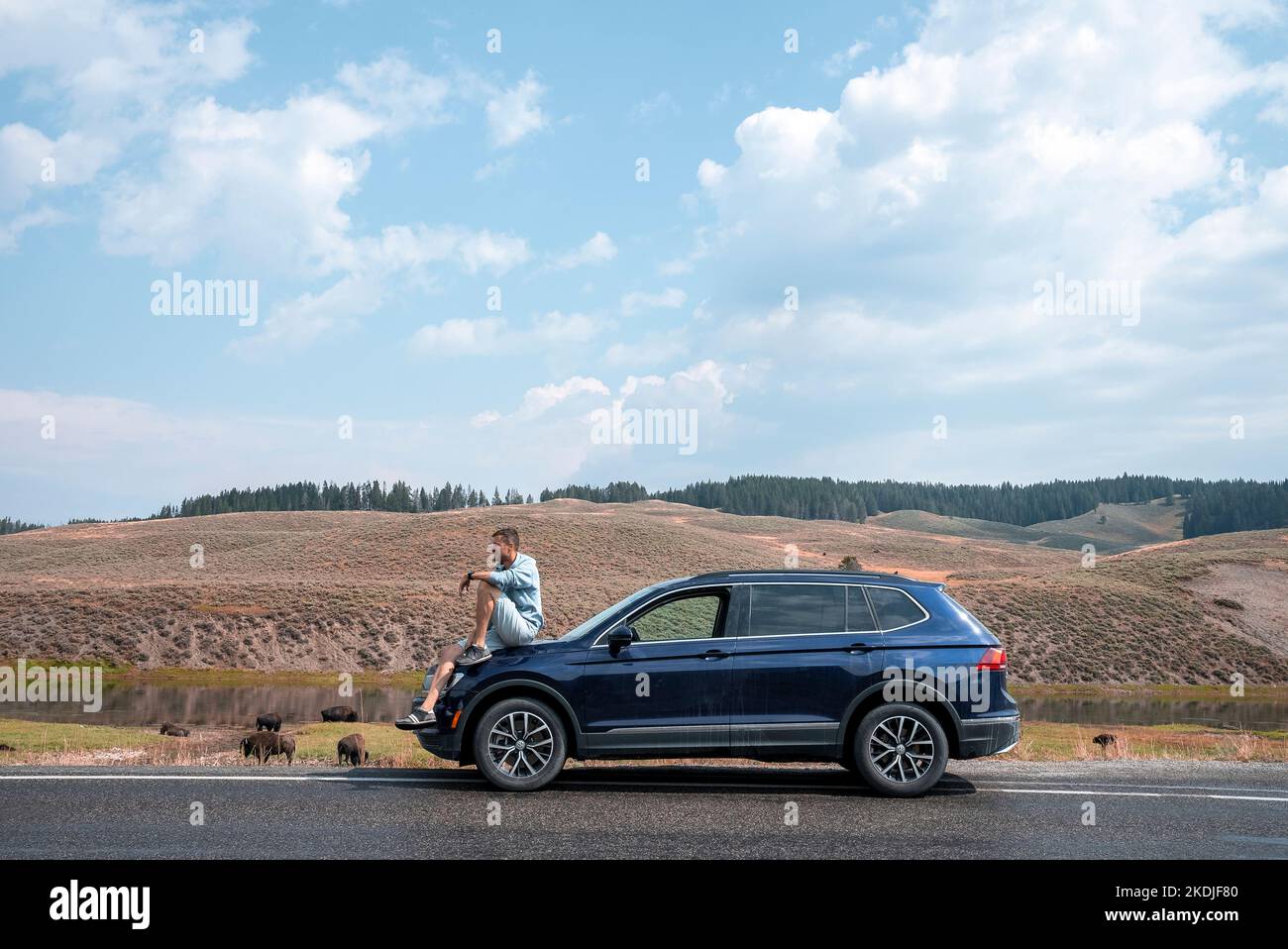Turista seduto in auto a bordo strada con montagna sullo sfondo a Yellowstone Foto Stock