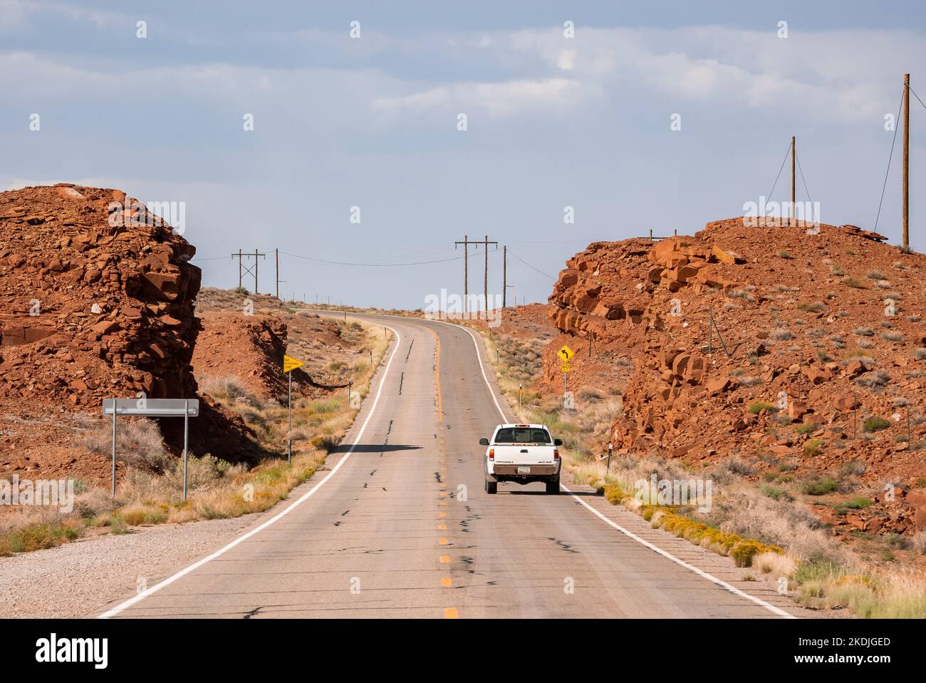 Auto che si muove su Country Road tra formazioni rocciose durante le giornate di sole Foto Stock