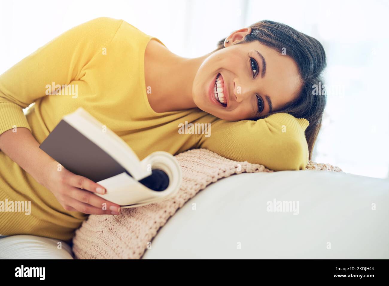 Leggo sempre almeno alcune pagine ogni giorno, una giovane donna che legge un libro mentre si rilassa a casa. Foto Stock