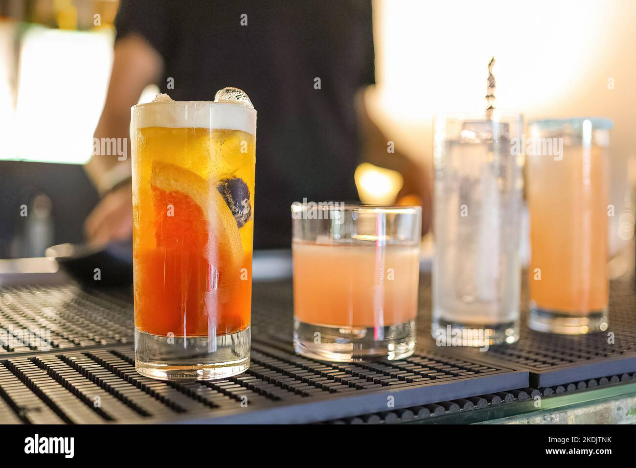 Quattro bicchieri da cocktail classici con barman fuori fuoco sullo sfondo Foto Stock