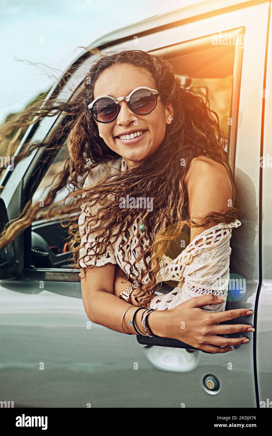 La libertà totale è ciò che segue. Ritratto di una giovane donna che si inclina fuori dal finestrino di un'auto mentre si è in viaggio. Foto Stock