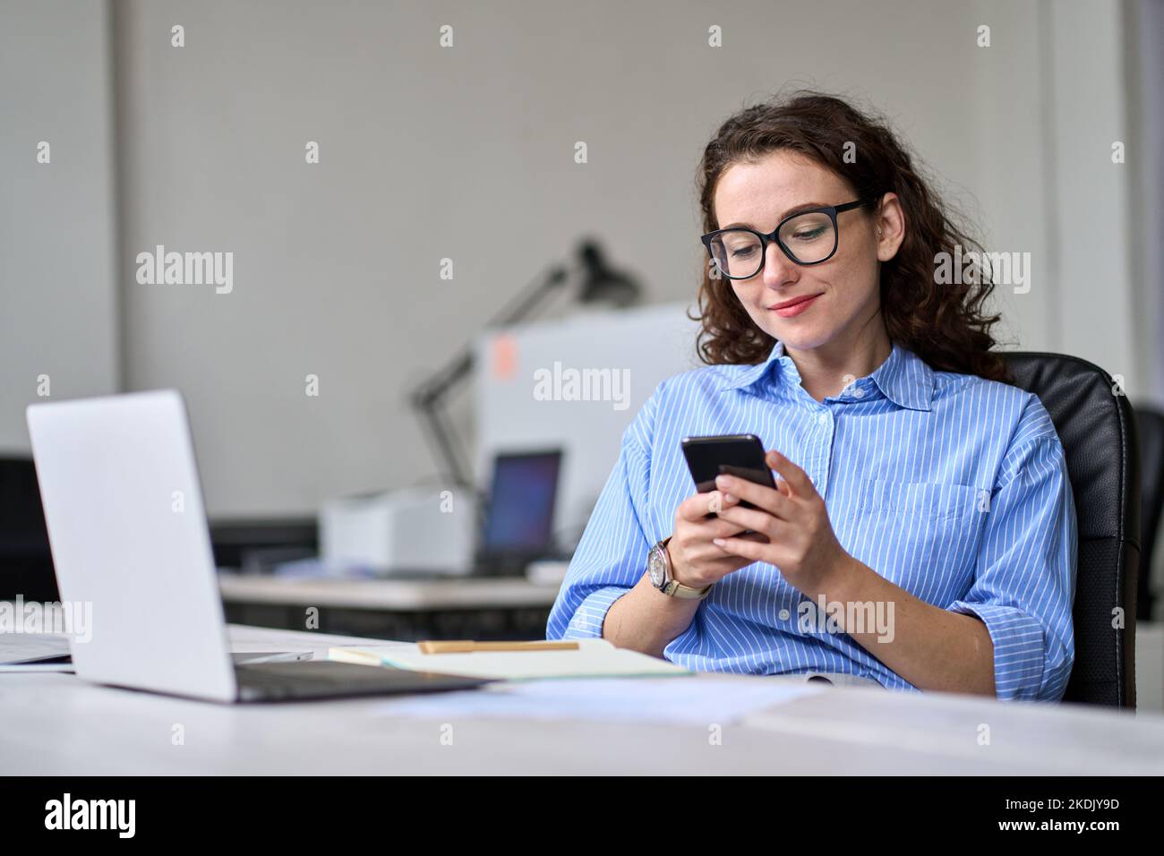 Giovane donna in viaggio d'affari che utilizza la seduta mobile alla scrivania in ufficio. Foto Stock