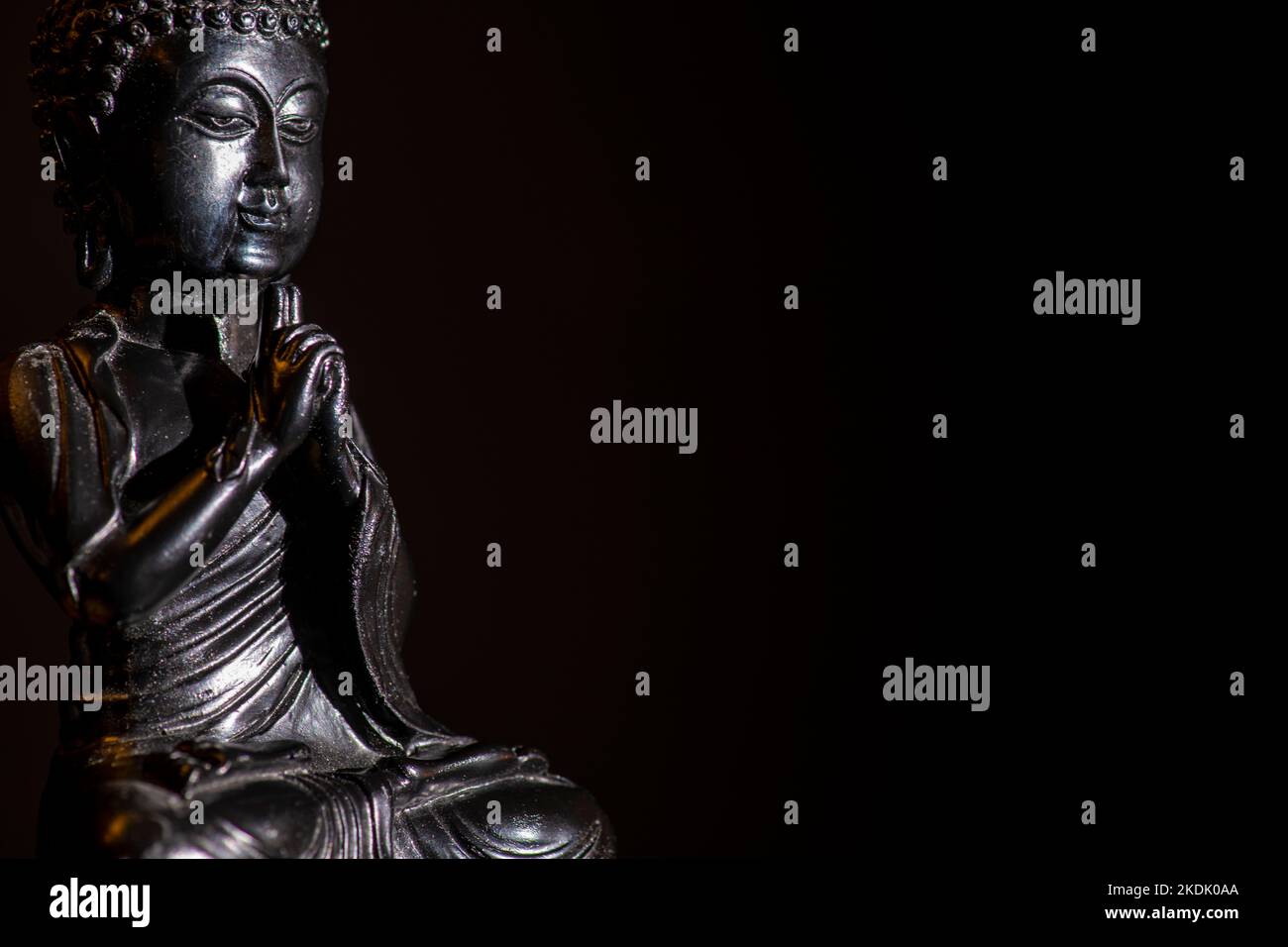 una piccola immagine di una statua nera del buddha con sfondo nero Foto Stock