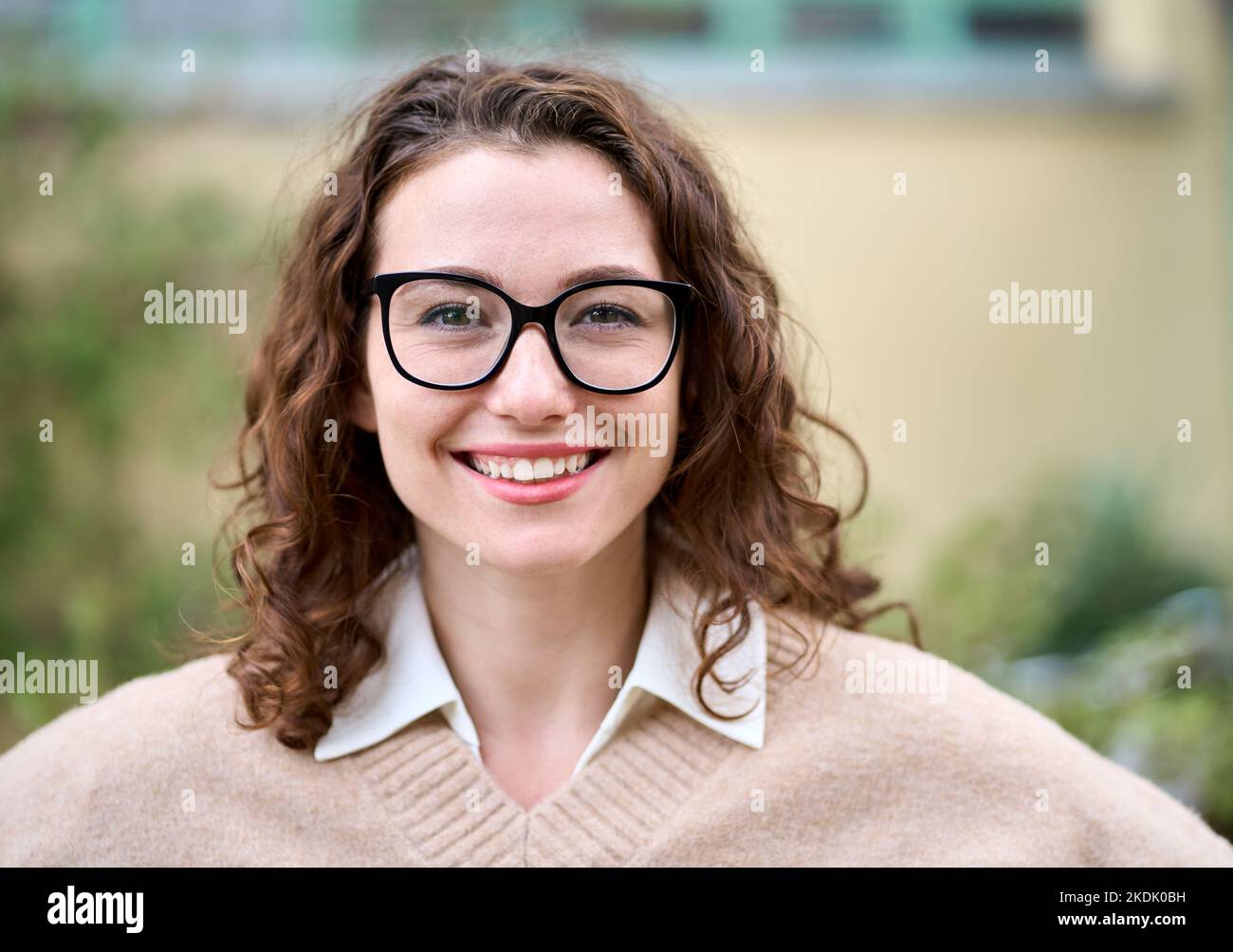 Giovane donna professionale sorridente in piedi all'aperto, ritratto alla testa. Foto Stock