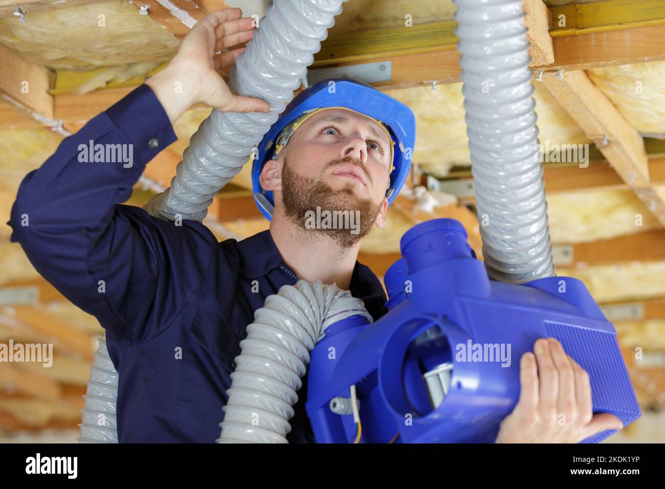 Tecnico di impianti di termoventilazione con flessibile per la dissipazione del calore in alluminio tubo in mano Foto Stock