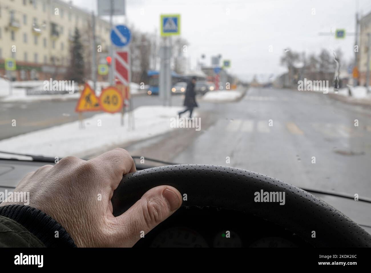 mano del conducente dietro il volante di un'auto che lascia il posto a un pedone in un passaggio pedonale Foto Stock