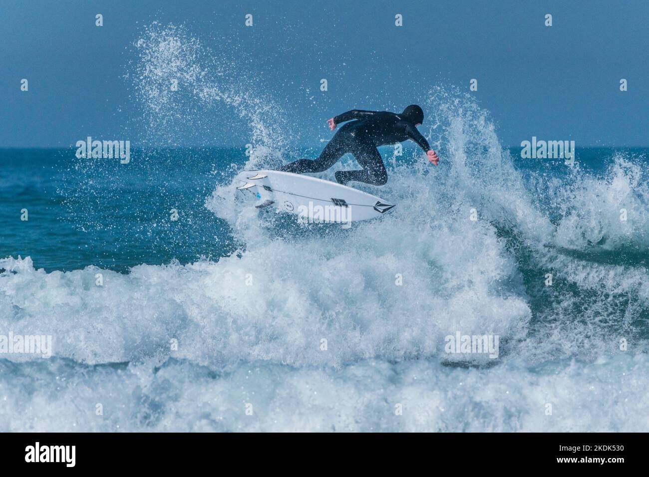Spettacolare azione di surf come surfista cavalca un'onda a Fistral a Newquay in Cornovaglia nel Regno Unito. Foto Stock