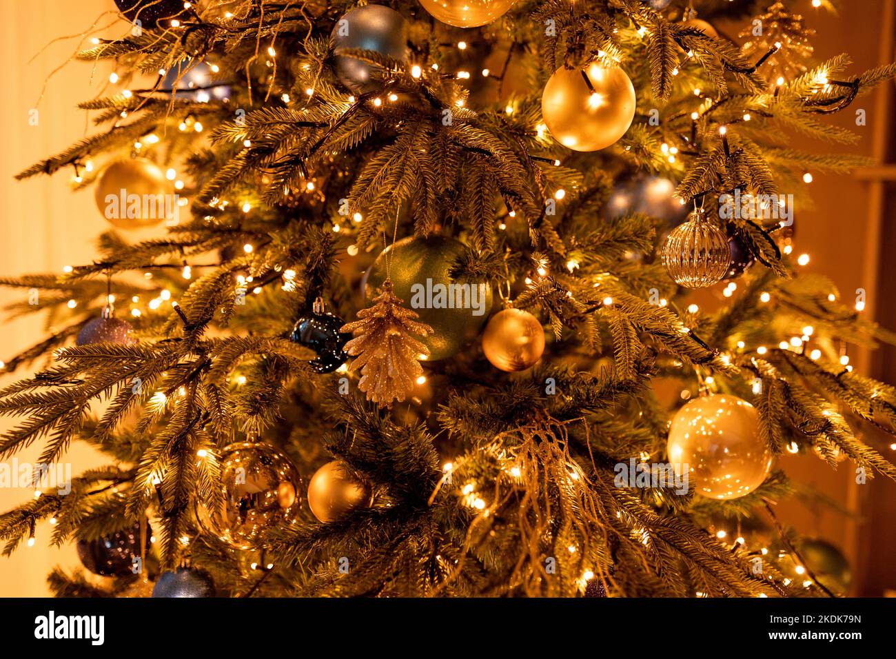 Bellissimo albero di Natale con giocattoli e ghirlande luminose in camera buia di sera Foto Stock