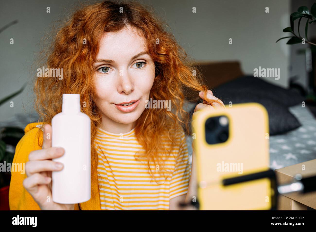 Donna rossa capelli blogger trasmette in diretta recensioni di prodotti di bellezza per capelli Foto Stock