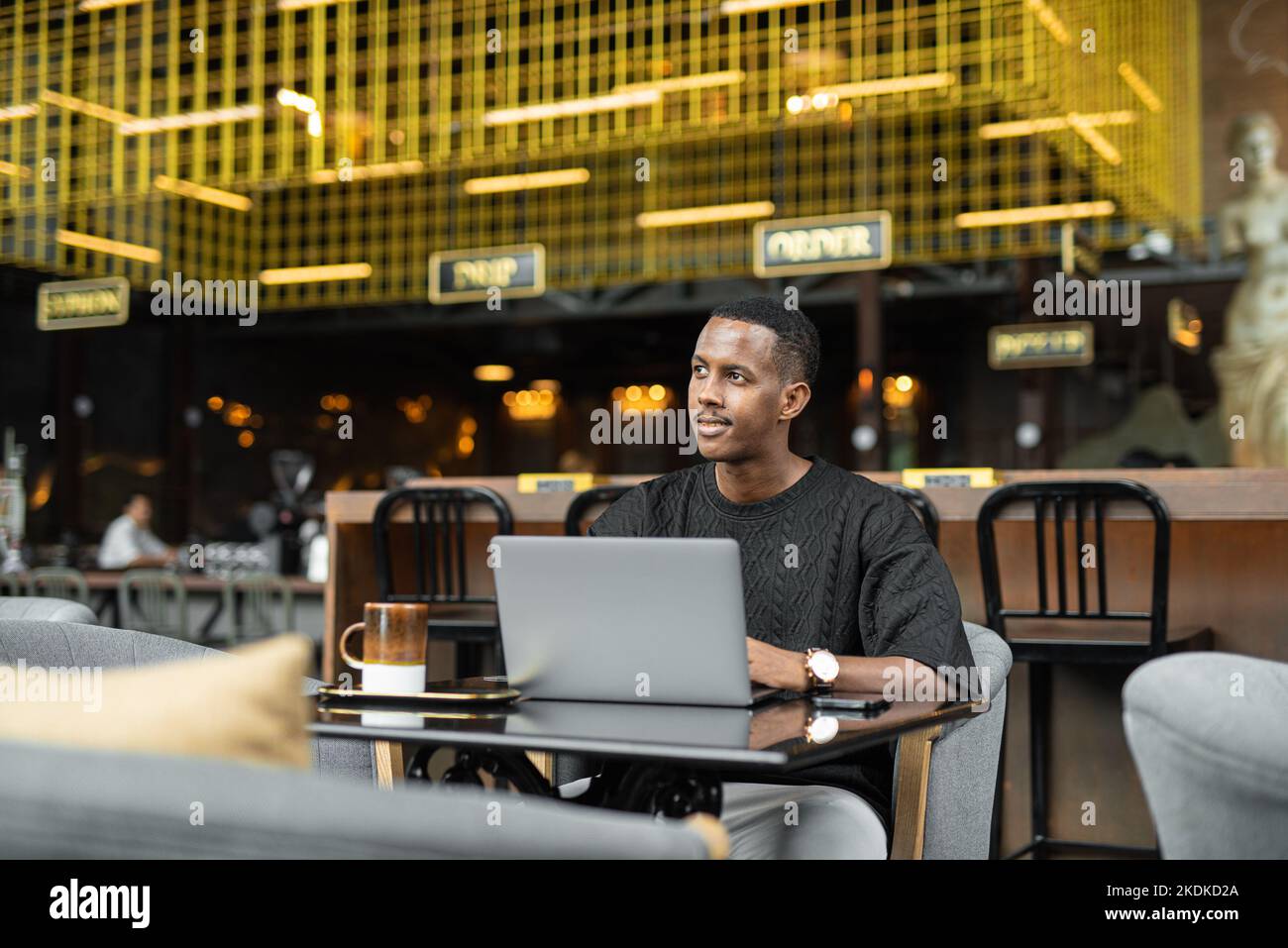 Ritratto di un bel giovane uomo nero che utilizza un computer portatile nel bar Foto Stock