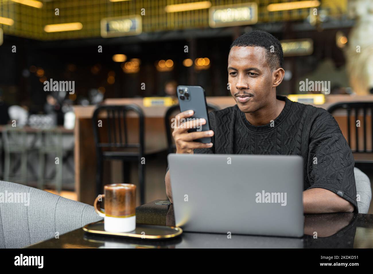 Ritratto di un bel giovane uomo nero che utilizza un computer portatile nel bar Foto Stock