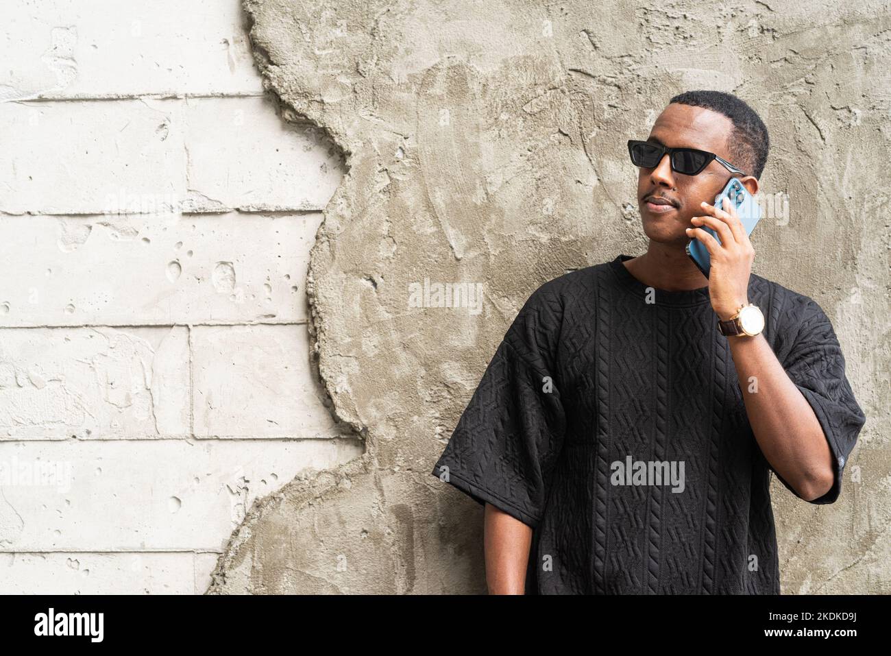 Bel giovane uomo africano che usa il telefono cellulare all'aperto Foto Stock