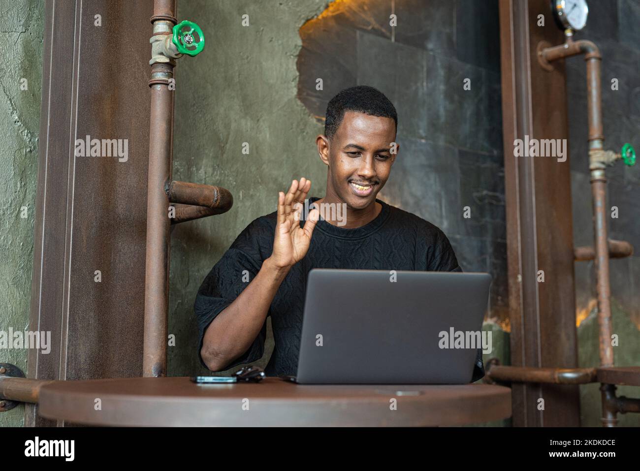 Ritratto di un bell'uomo nero seduto e che utilizza un computer portatile in interni Foto Stock
