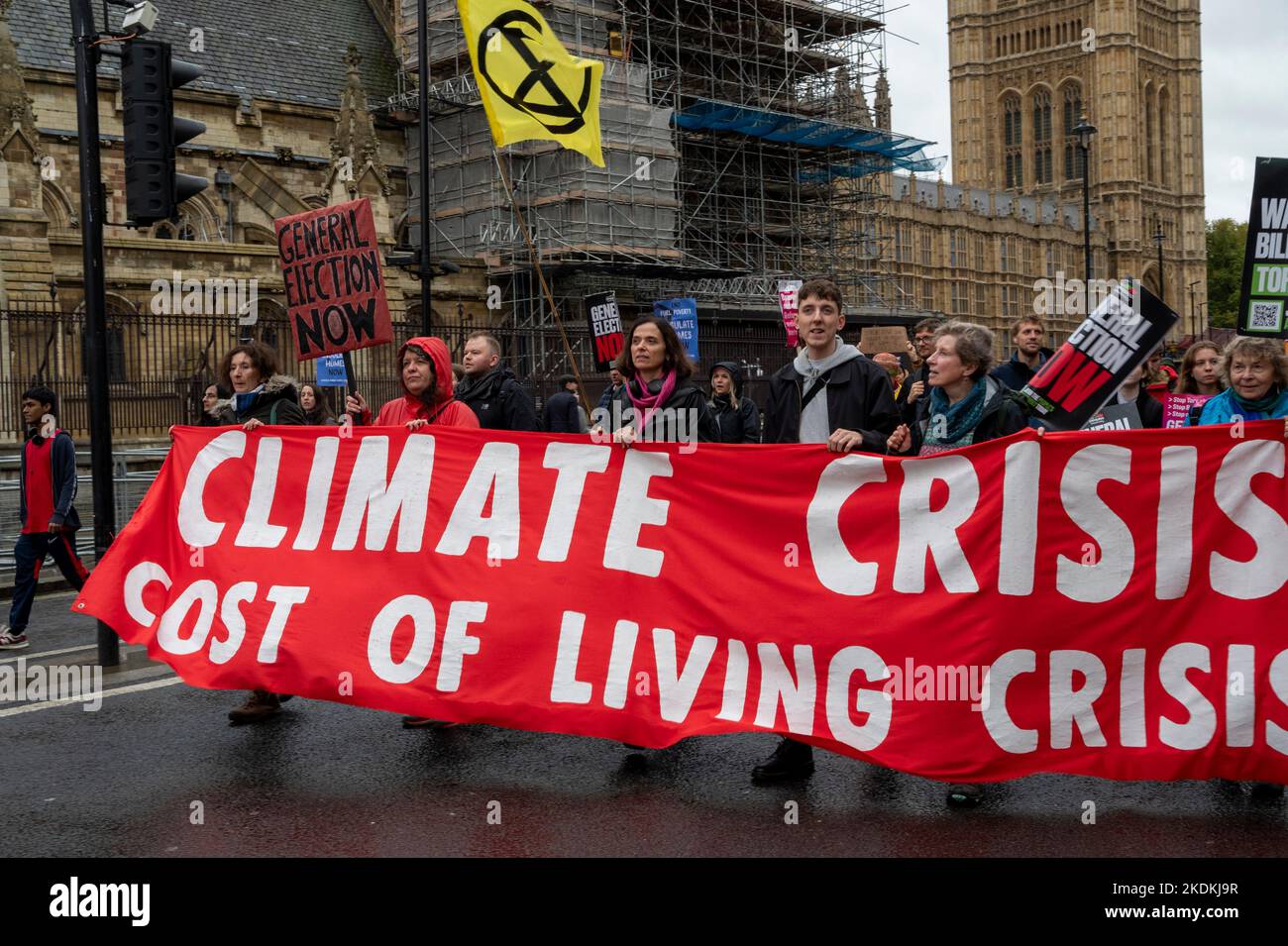 Extinction ribellion attivista con un banner 'crisi climatica, costo della vita crisi' marciando al di fuori del Parlamento UK. Foto Stock