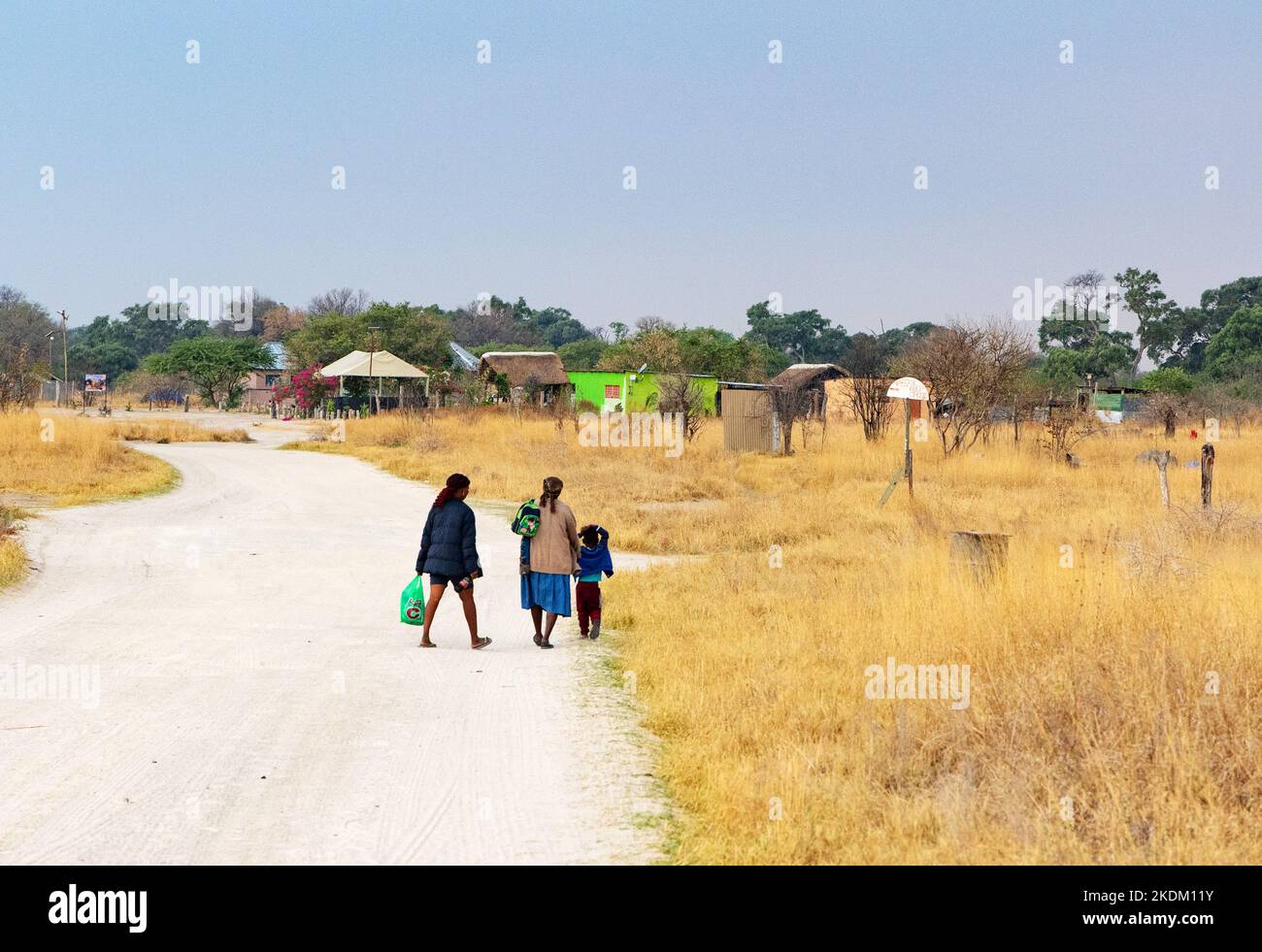 Scena del villaggio africano - persone che camminano lungo la strada verso il villaggio di Kwai, il Delta di Okavango, l'Africa del Botswana. Stile di vita africano. Foto Stock