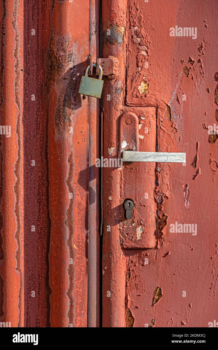 Vecchio cancello in ferro arrugginito con maniglia vintage e lucchetto chiuso Foto Stock