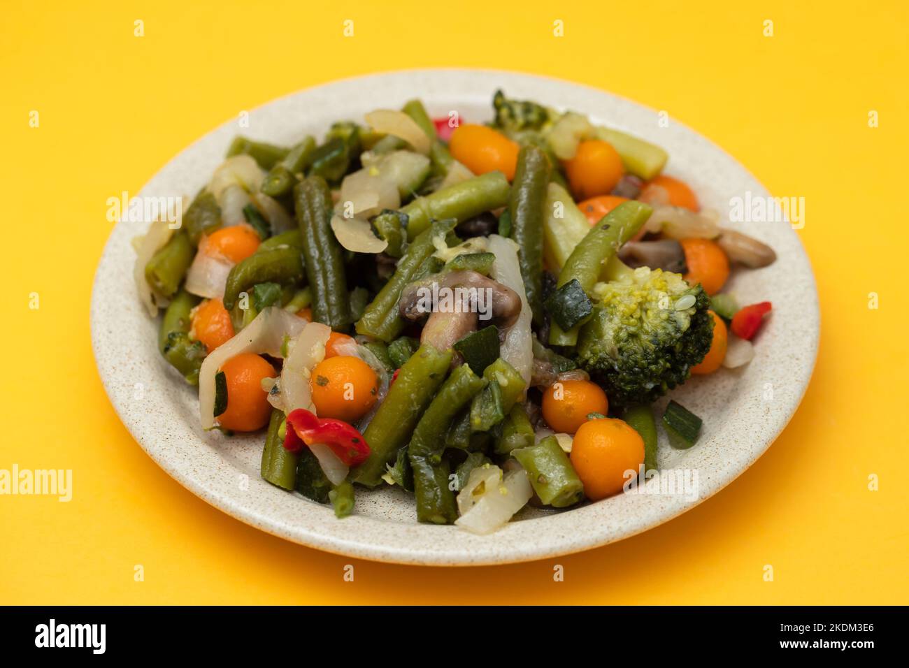 Verdure bollite miste su piatto marrone chiaro su giallo Foto Stock