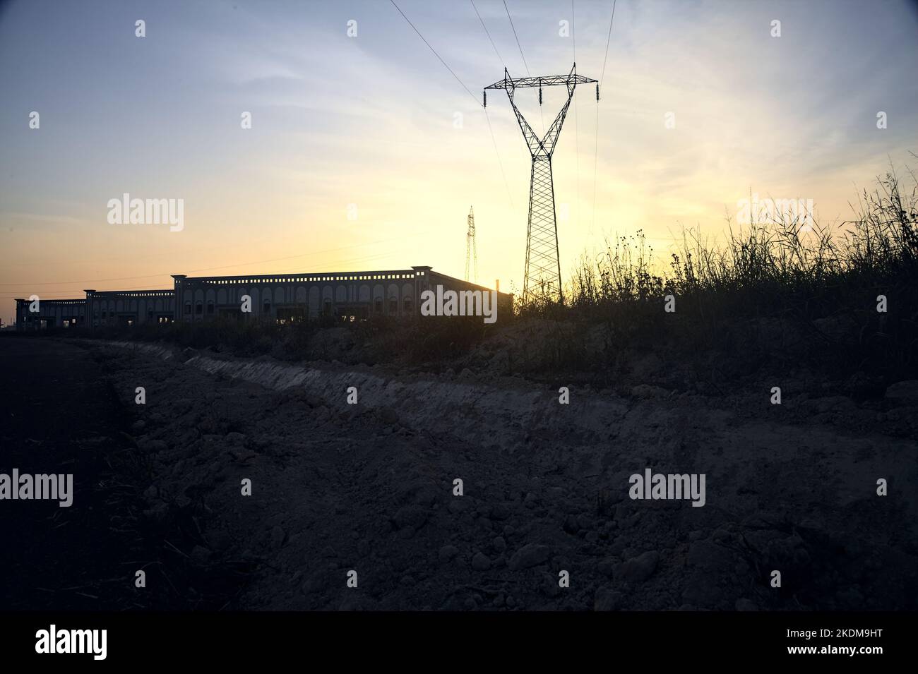 Magazzini abbandonati e un pilone alla periferia di una città italiana al tramonto Foto Stock