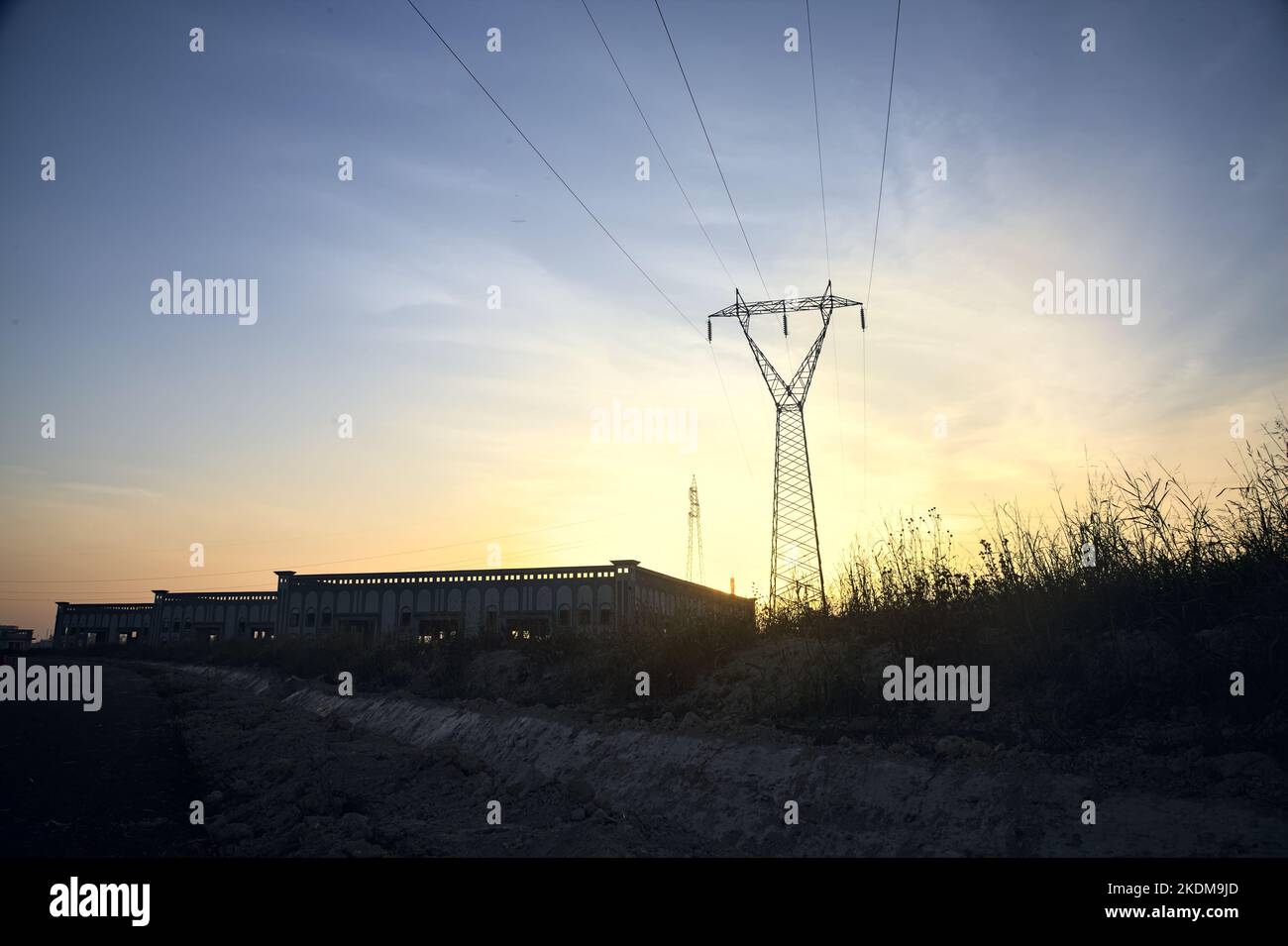 Magazzini abbandonati e un pilone alla periferia di una città italiana al tramonto Foto Stock