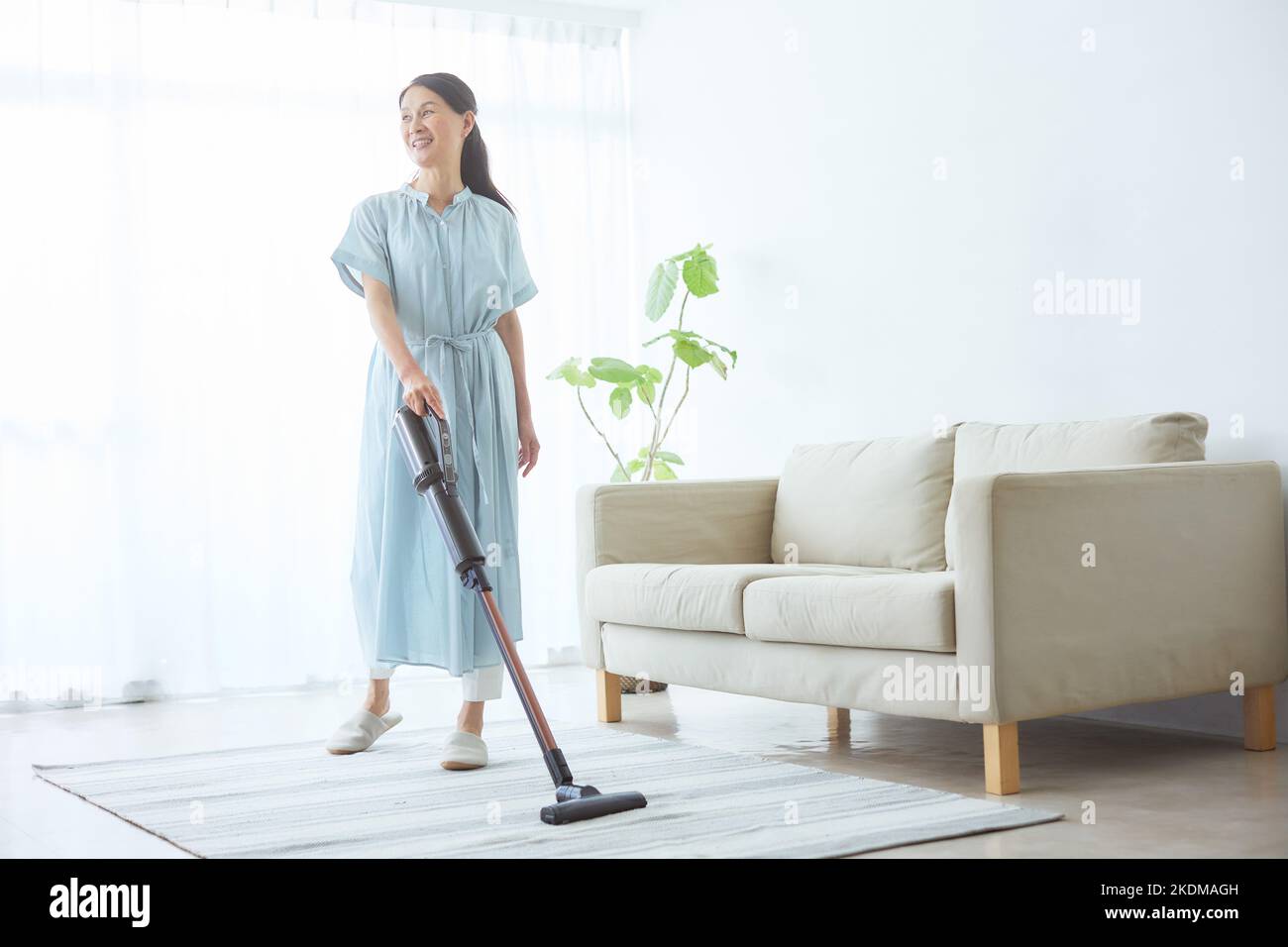 Donna giapponese senior pulizia a casa Foto Stock