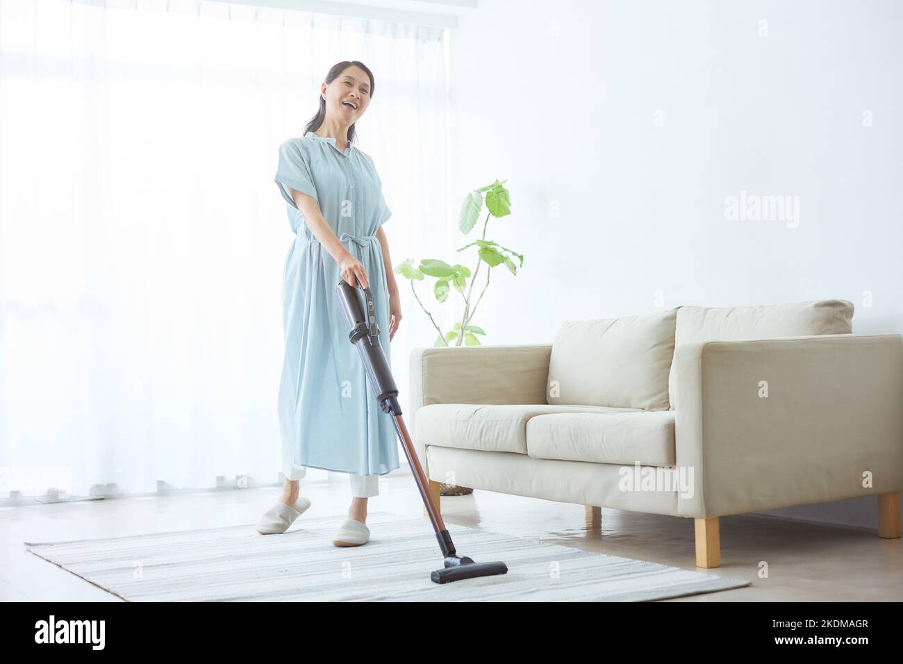 Donna giapponese senior pulizia a casa Foto Stock